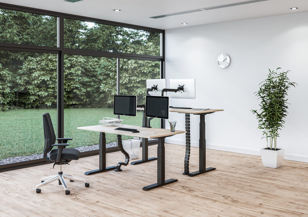 professionele kantoorruimte met verstelbare bureaus en bureaustoel.