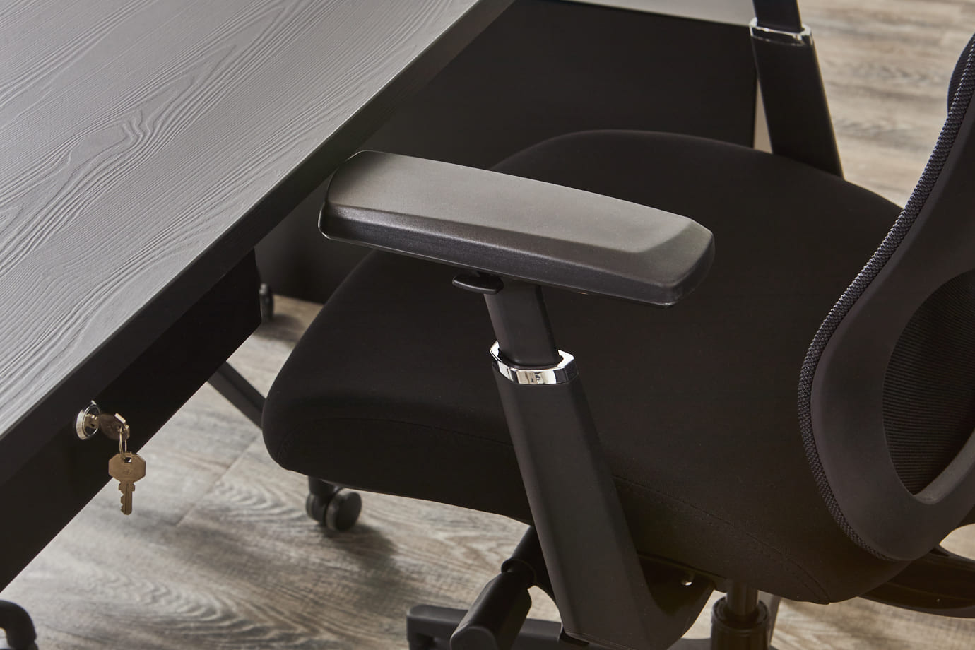 Zwarte bureaustoel armleuning bij een bureau met lade